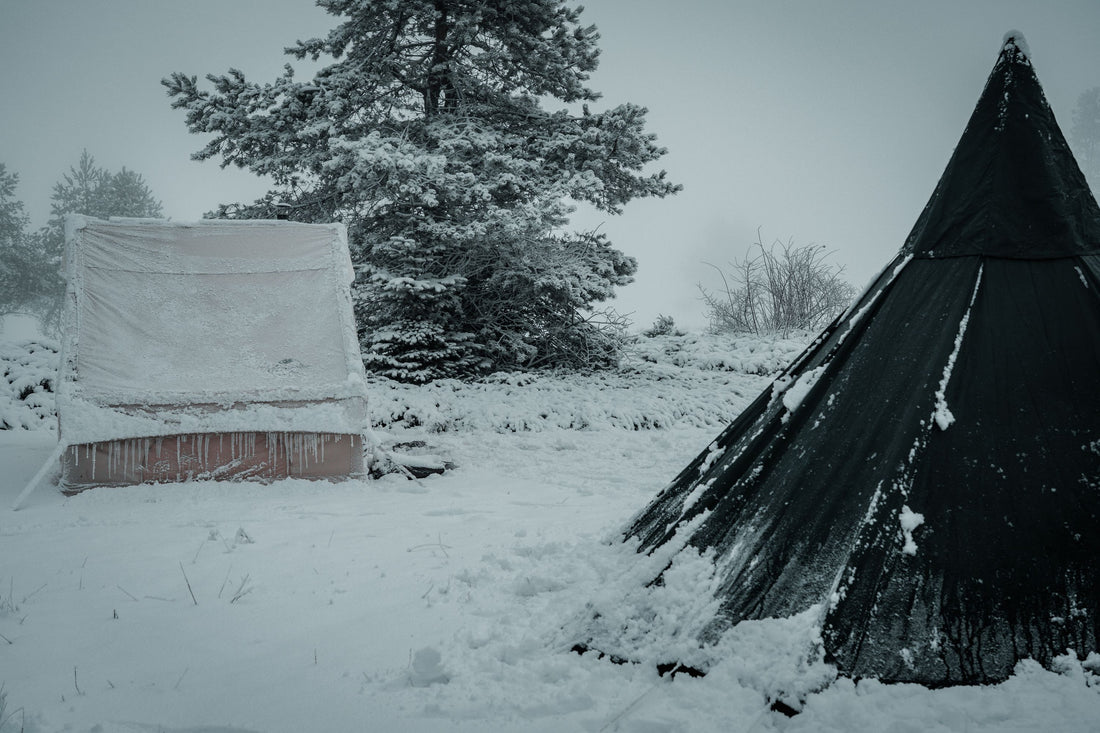 Snow-covered tents in a winter landscape, showcasing a serene and chilly outdoor camping scene.
