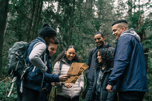 Friends exploring a forest trail with a map, enjoying nature and adventure together.
