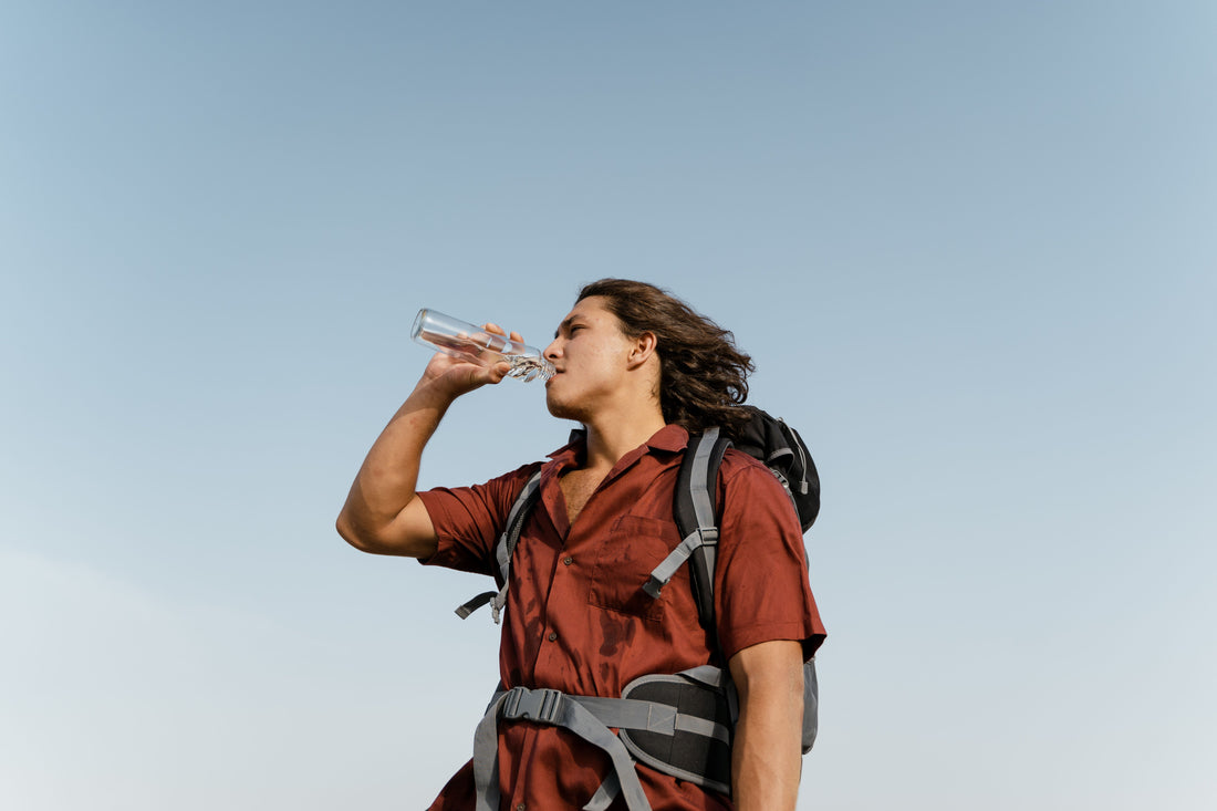 Young backpacker staying hydrated while traveling under clear skies.